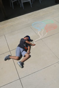 A kid talking a photo with the balloon chalk art